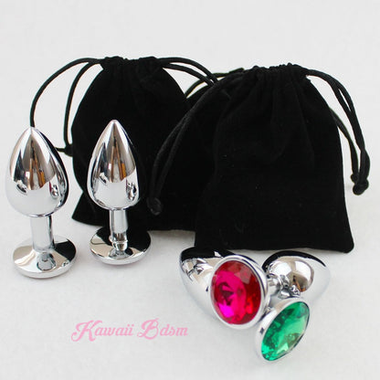 Classic jewel stainless steel plugs with red and green bases displayed next to their protective black velvet drawstring pouches.