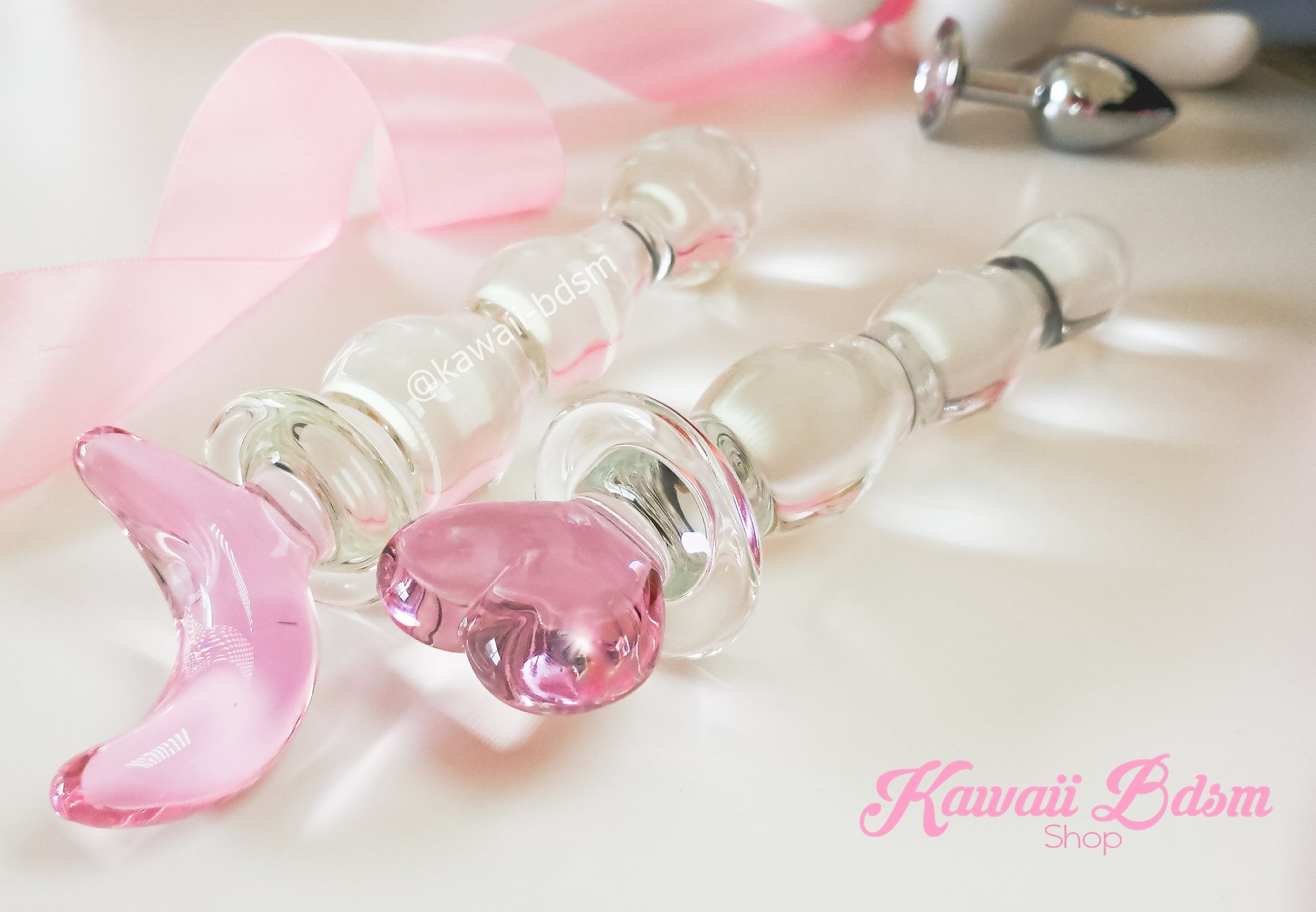 Close-up of the translucent pink glass moon handle with a decorative satin ribbon.