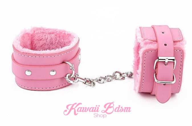 A pair of pastel pink fluffy faux leather cuffs standing upright, highlighting the soft interior lining and sturdy metal clasps.