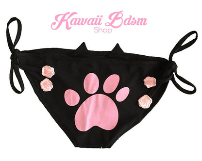 Flat lay back product view of the black neko cosplay panties, highlighting the adorable pink kitten paw print design stamped perfectly on the cheeky booty and the black adjustable side tie strings.