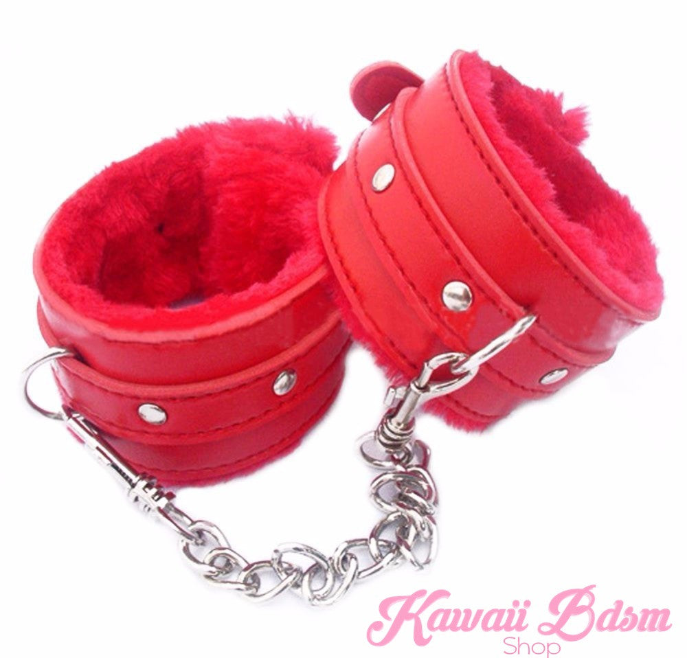 A pair of bright crimson red faux leather restraint cuffs with matching soft fluffy lining and sturdy silver metal chain connectors.