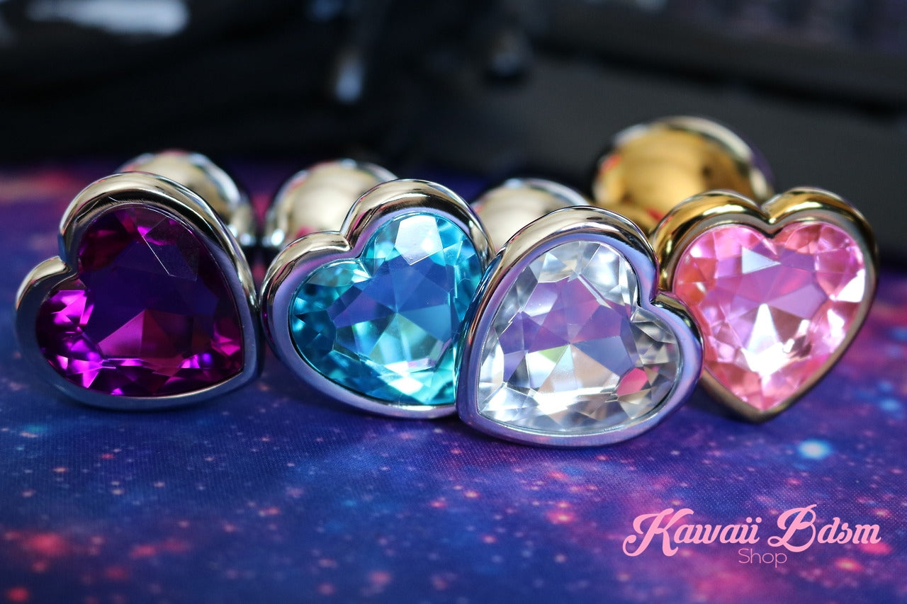Macro close-up of sparkling purple, blue, and pink crystal heart plugs shining brilliantly against a dark aesthetic background.